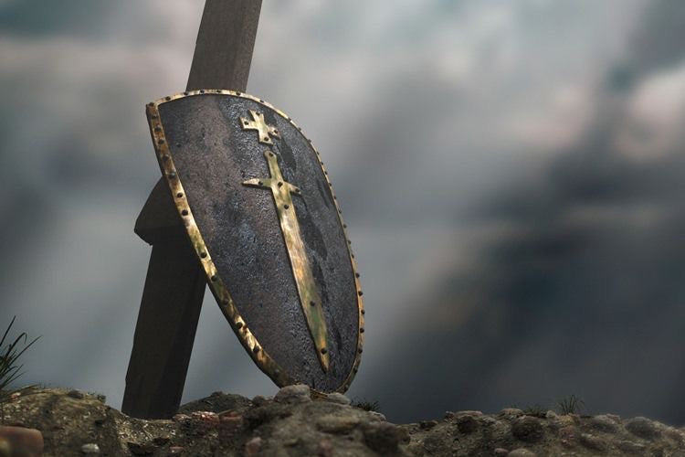 A shield and sword resting on a rocky ground with a cloudy backdrop, representing strength and faith. Be Still and know that He is God.